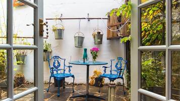 Eine Terrasse mit Tisch und Stühlen, umgeben von Kübelpflanzen und hängenden Pflanzgefäßen.