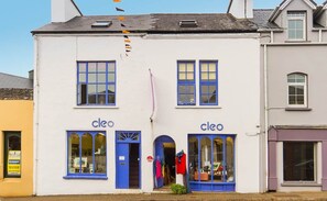 A two-story building with 'cleo' signage on the ground floor, featuring large windows and a visible storefront.