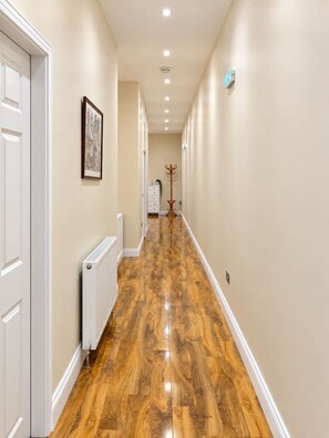 A hallway with wooden flooring, white walls, and a radiator. - Stylish Modern Apartment (Edinburgh)