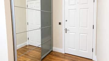 A room with a sliding glass door closet, a white door, and wooden flooring.