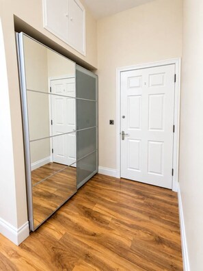 A room with a sliding glass door closet, a white door, and wooden flooring. - Stylish Modern Apartment (Edinburgh)