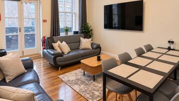 A modern living room with a sofa, coffee table, and dining table.