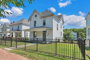A row of white two-story houses with a black metal fence in front. - Stay Roanoke | Patterson Pad | Roomy 3BR in Town (Roanoke)