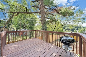 A wooden deck with a barbecue grill, surrounded by trees and a view of a residential area. - Stay Roanoke | 4BR near River, Greenway, Families (Roanoke)