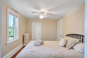 A bedroom with a bed, a ceiling fan, a radiator, and a window. - Stay Roanoke | 4BR near River, Greenway, Families (Roanoke)