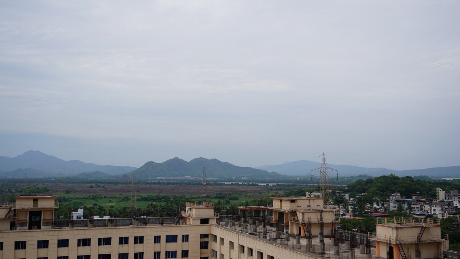 A view of a residential area with multiple buildings, some under construction, and a distant mountain range.