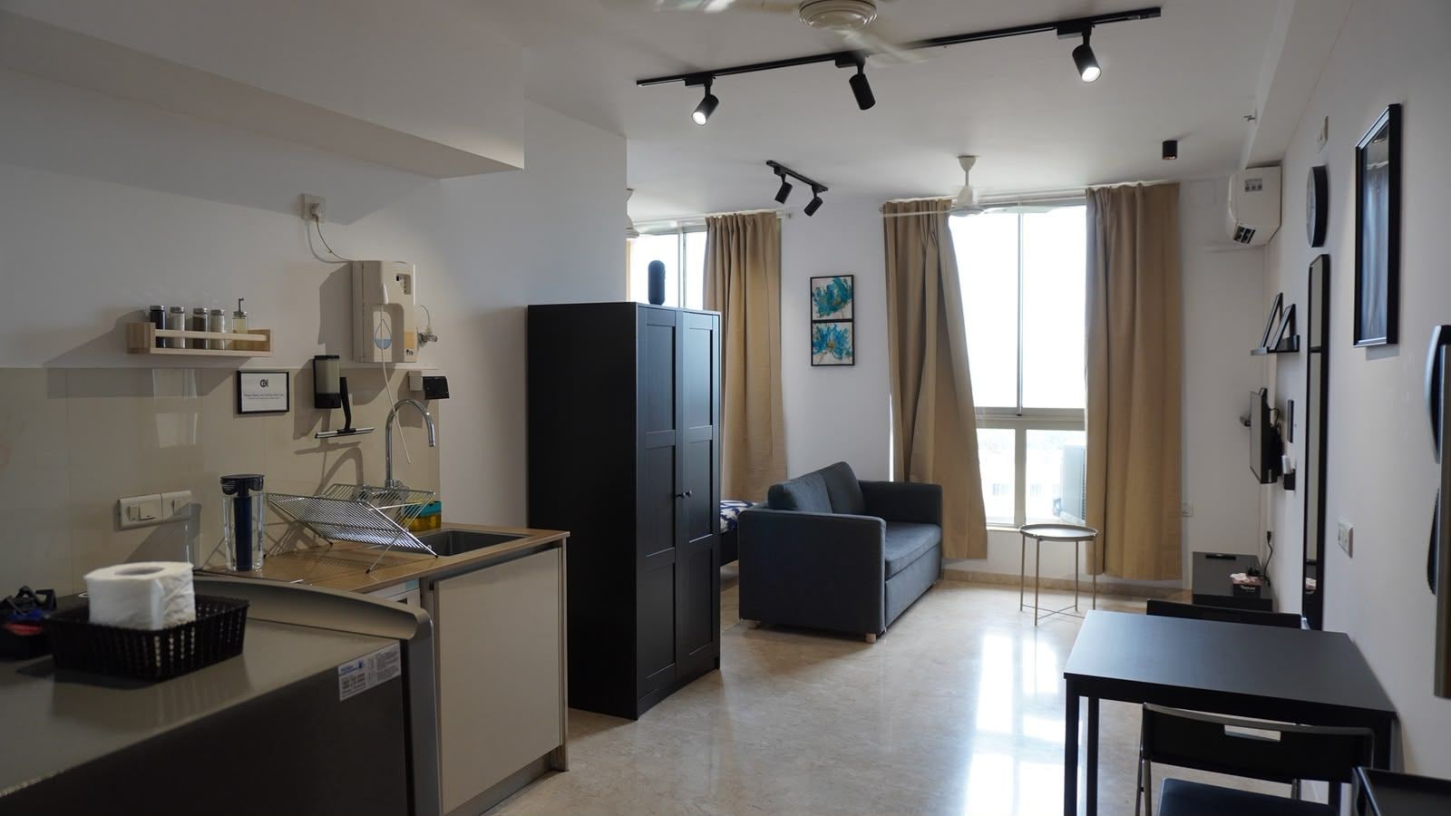 A compact living space with a kitchenette, a sofa, and a dining table.
