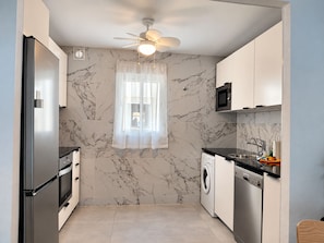Una cocina compacta con refrigerador, horno, microondas y lavavajillas.
