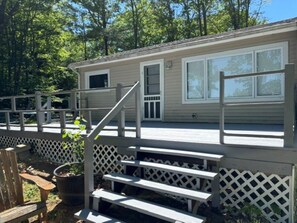 A single-story mobile home with a porch, a small deck, and a fenced yard. - Cozy 3-bedroom lake house in charming Canterbury (Canterbury)