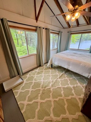 A bedroom with a bed, a ceiling fan, and windows with curtains. - Cozy 3-bedroom lake house in charming Canterbury (Canterbury)