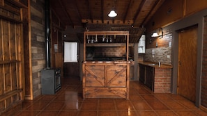 A rustic kitchen with a wooden island, a stove, and a brick wall. - Hermosa y amplia casa con vista al lago (El Calafate)