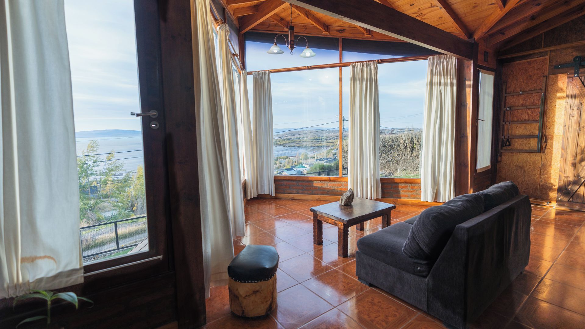 A room with a large window, a sofa, a table, and a bench.
