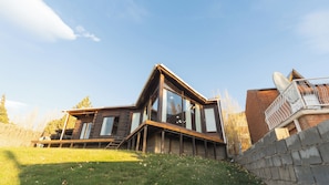 A modern log cabin with a sloped roof, large windows, and a deck. - Hermosa y amplia casa con vista al lago (El Calafate)