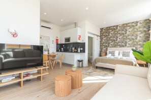 A modern living room with a flat-screen TV, a sofa, and a dining area with a table and chairs. - Proteia Studio by Atlantic Holiday (Santa Cruz)