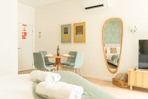 A hotel room with a bed, a round dining table with chairs, a television, and a large mirror. - Rosa Studio by Atlantic Holiday (Santa Cruz)
