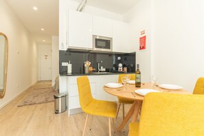 Eine moderne Küche mit weißen Schränken, einer Mikrowelle und einem Essbereich mit gelben Stühlen und einem Holztisch.