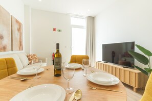 A dining area with a table set for two, a bottle of wine, and a television on a wooden stand. - Orqu dea Studio by Atlantic Holiday (Santa Cruz)