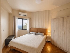 Una camera da letto con un letto, un comodino, una lampada, un armadio e una finestra con tende.