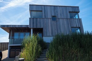 A modern two-story building with a sloped roof, large windows, and a visible staircase leading to the entrance. - Villa Topduin, with a sauna, close to the sea (Bergen aan zee)