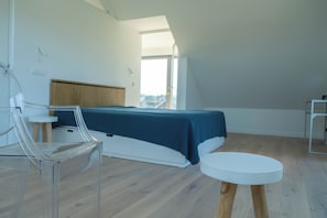 A modern bedroom with a bed, a chair, a small table, and a view of the outdoors. - Villa Topduin, with a sauna, close to the sea (Bergen aan zee)
