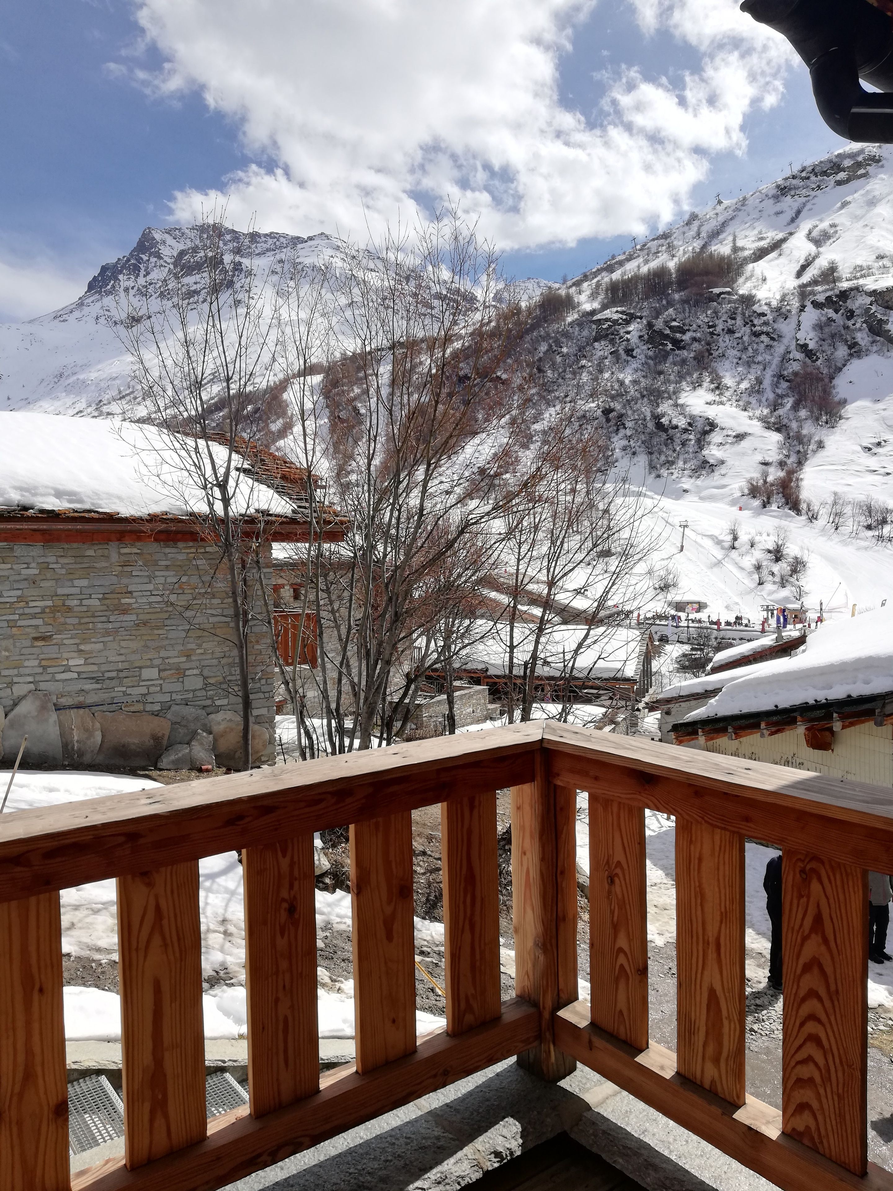 Un balcon en bois offrant une vue sur une montagne enneigée et un bâtiment en pierre.