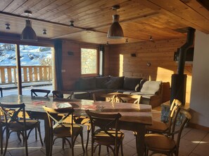 A cozy wooden interior with a dining area, sofas, and a fireplace.