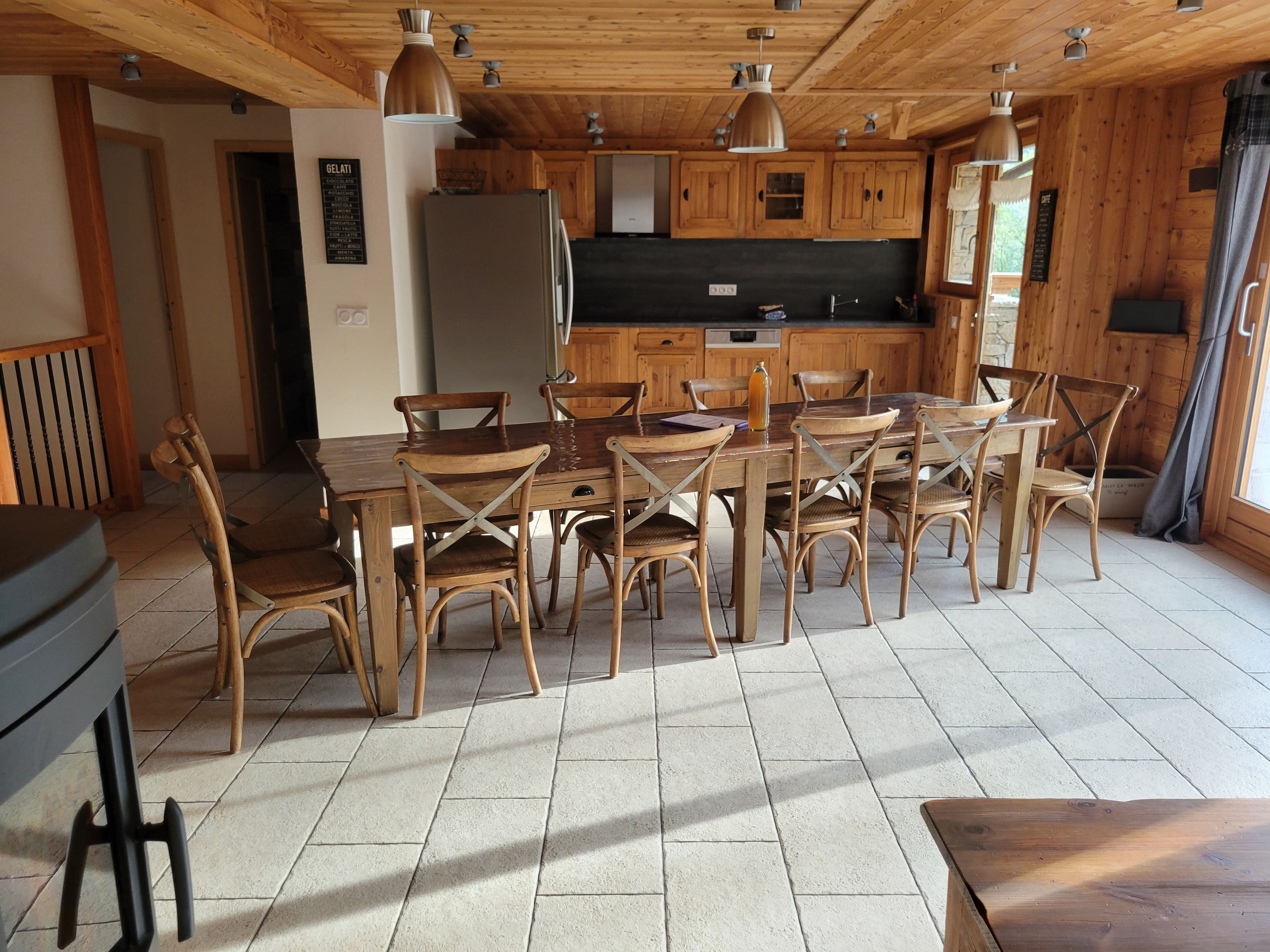 Ein Holzinterieur mit einem Esstisch, Stühlen, einem Kühlschrank und einer Küchenzeile mit Schränken und einer Arbeitsplatte.