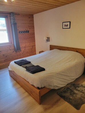 Una habitación con paneles de madera, una cama, una lámpara de pared y un cuadro enmarcado.