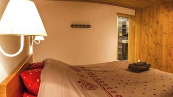 Ein Schlafzimmer mit einem Bett, einer Wandleuchte, einem Bild und einer Holzwand.