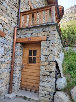 A stone building with a wooden door and a balcony.