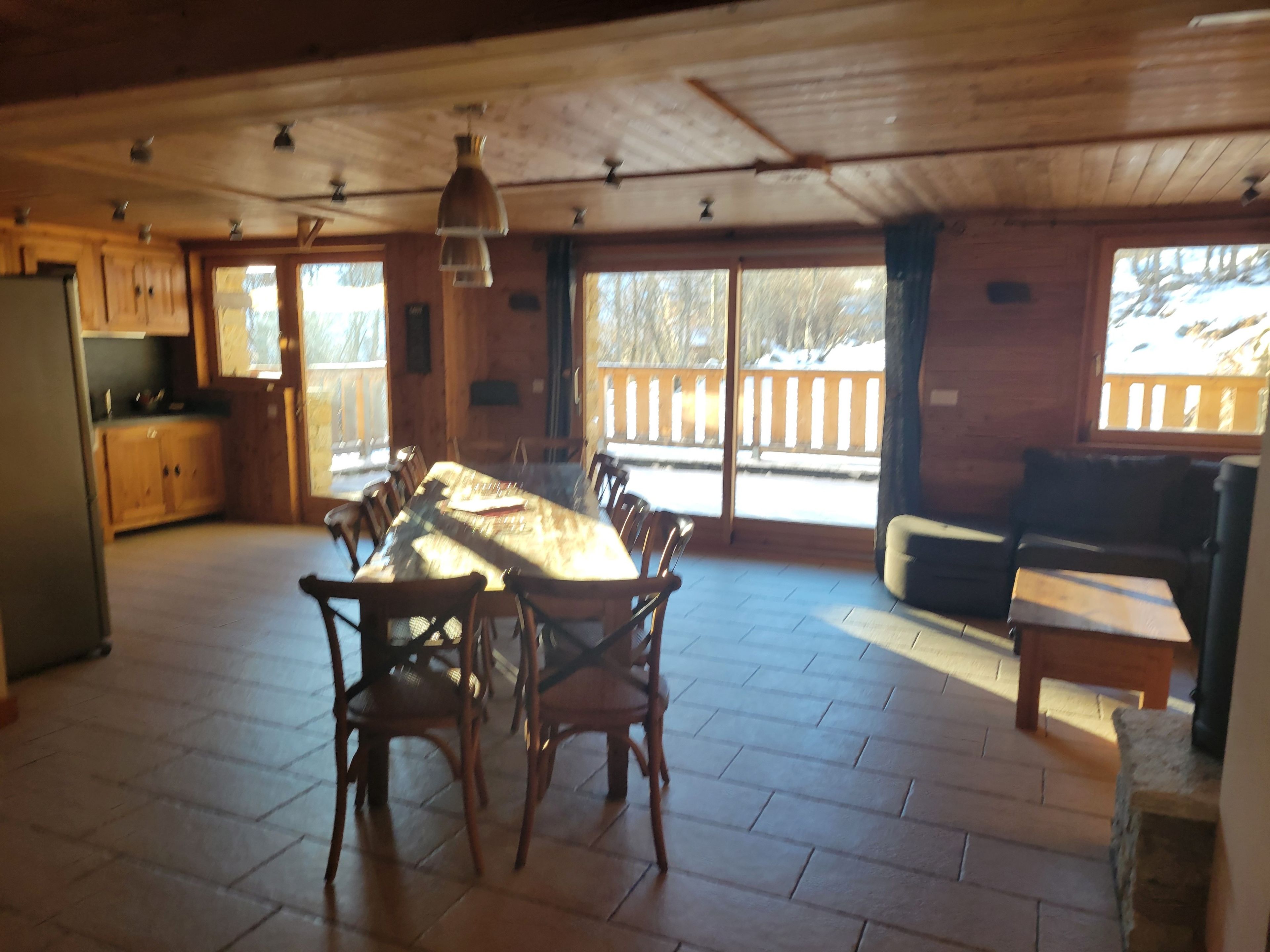 Ein geräumiger Essbereich mit großem Tisch und Stühlen, Holzboden, Deckenventilator und Blick auf eine verschneite Landschaft durch die Fenster.