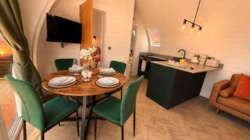 Un comedor con una mesa redonda, sillas y un televisor montado en la pared.