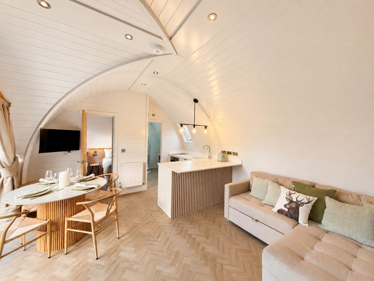 A modern loft-style living space with a dining area, kitchenette, and a cozy seating area.