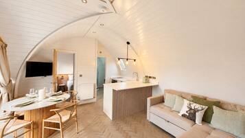 A modern loft-style living space with a dining area, kitchenette, and a cozy seating area.