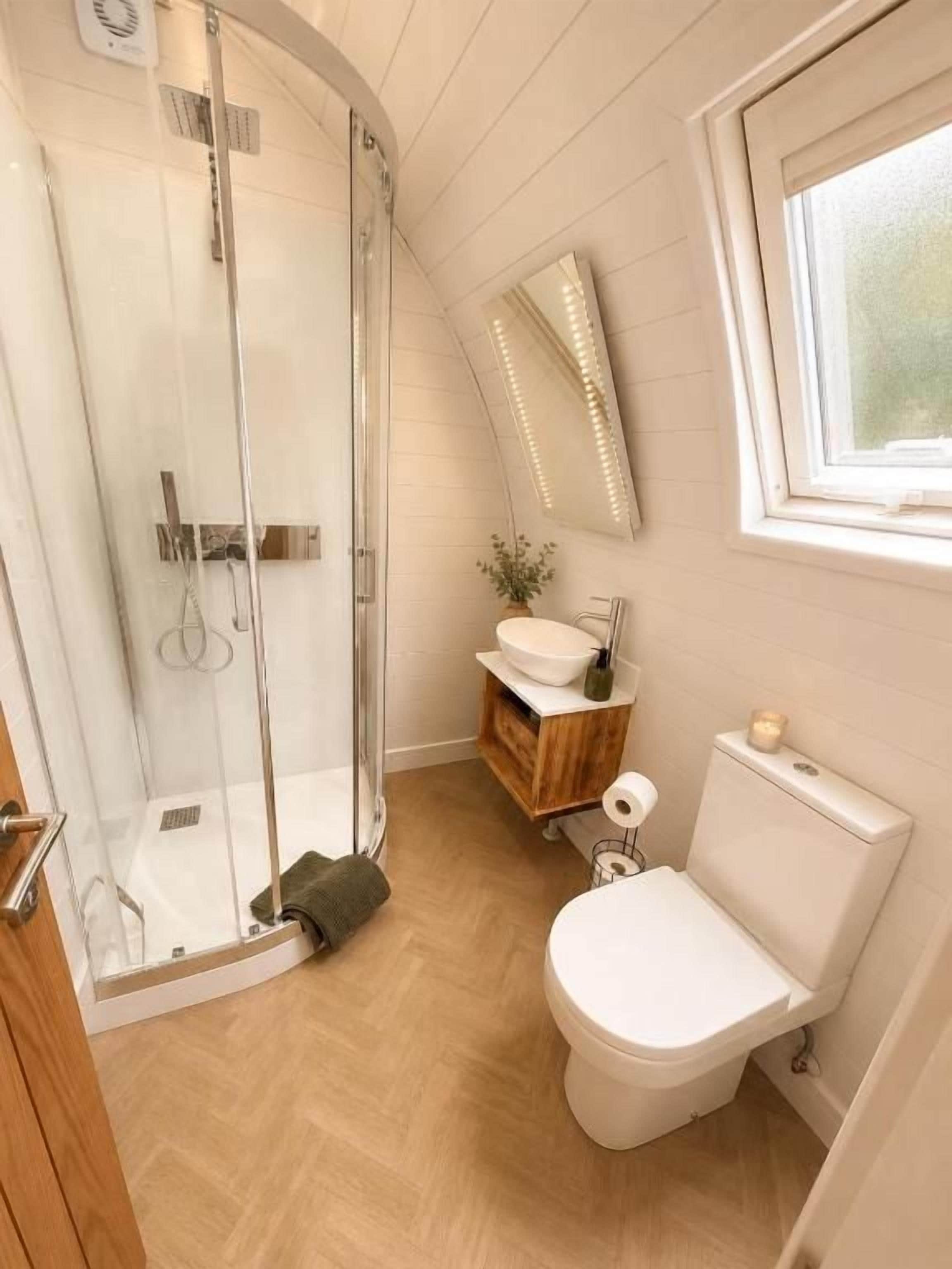 Un baño con cabina de ducha de vidrio, inodoro, lavabo y espejo.