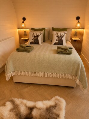Un dormitorio con una cama grande, dos mesitas de noche y una alfombra de piel en el suelo.