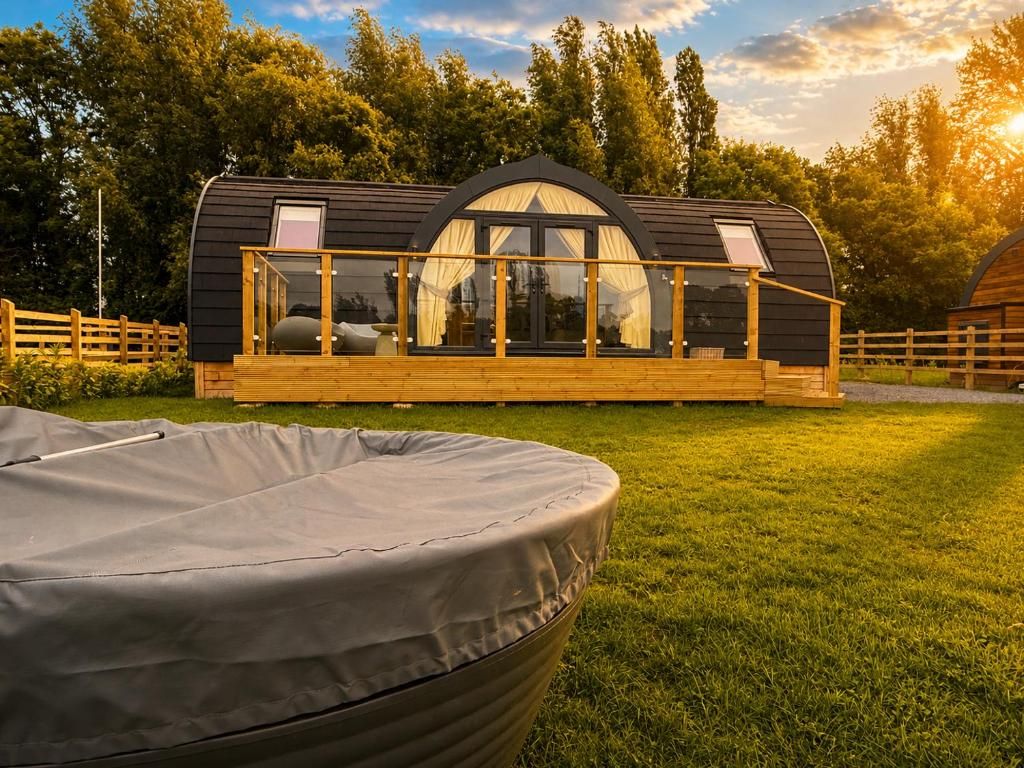 Une petite cabane moderne dotée d’un espace extérieur couvert avec des sièges et d’une grande fenêtre.