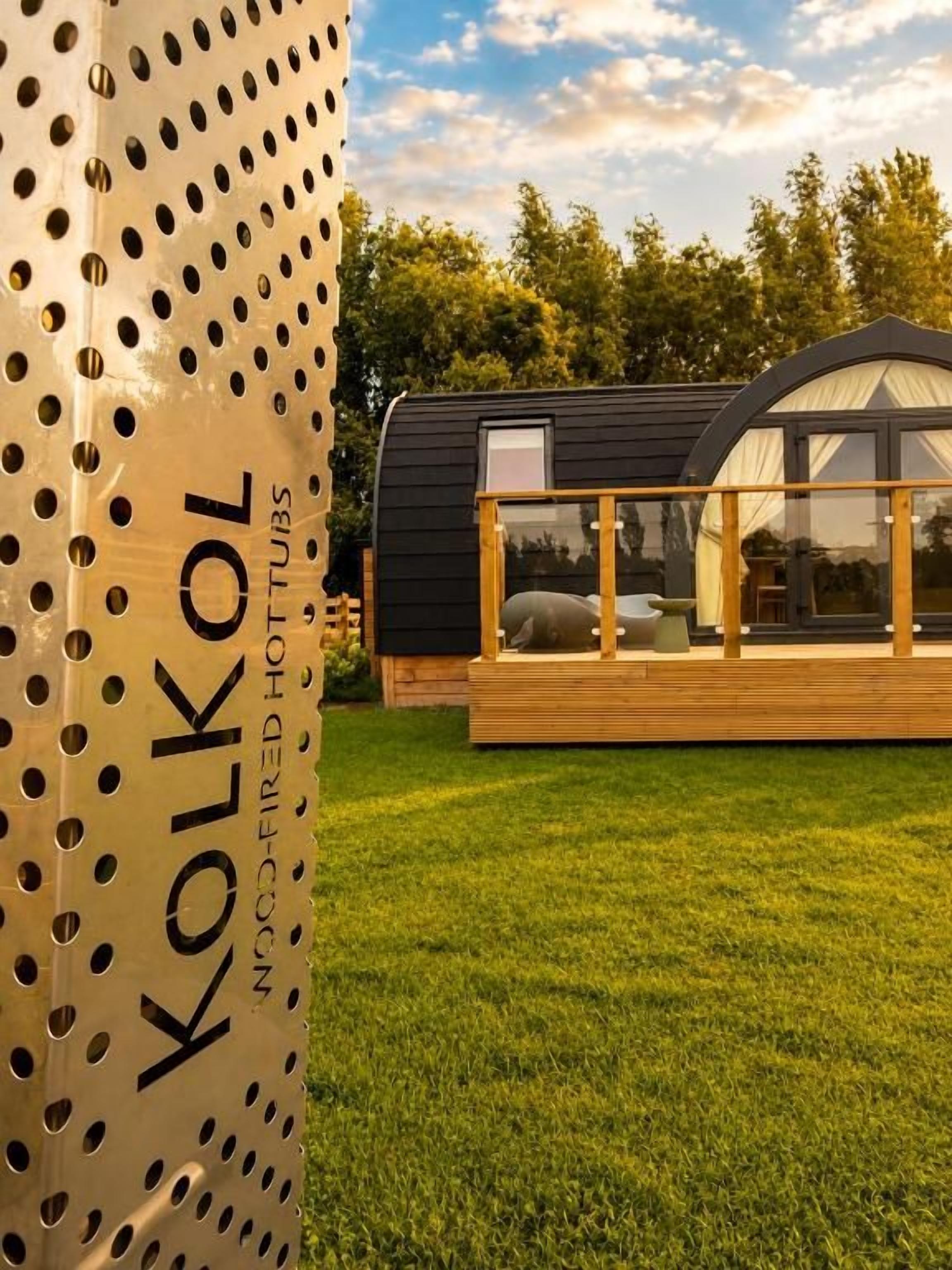 Une structure moderne et compacte, dotée d’un toit plat, d’une grande fenêtre et d’une terrasse en bois.