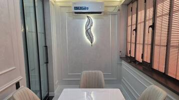 A conference room with a marble table, cushioned chairs, a decorative wall piece, and a window with blinds.
