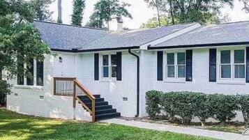 A single-story house with a front porch, a staircase leading to the entrance, and a well-maintained lawn.