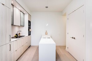 Eine moderne Küche mit weißen Schränken, einer zentralen Kochinsel und einer Pendelleuchte.