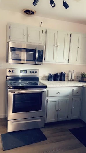 A kitchen with stainless steel appliances, white cabinets, and a black mat on the floor. - Heloise Haven (Rome)