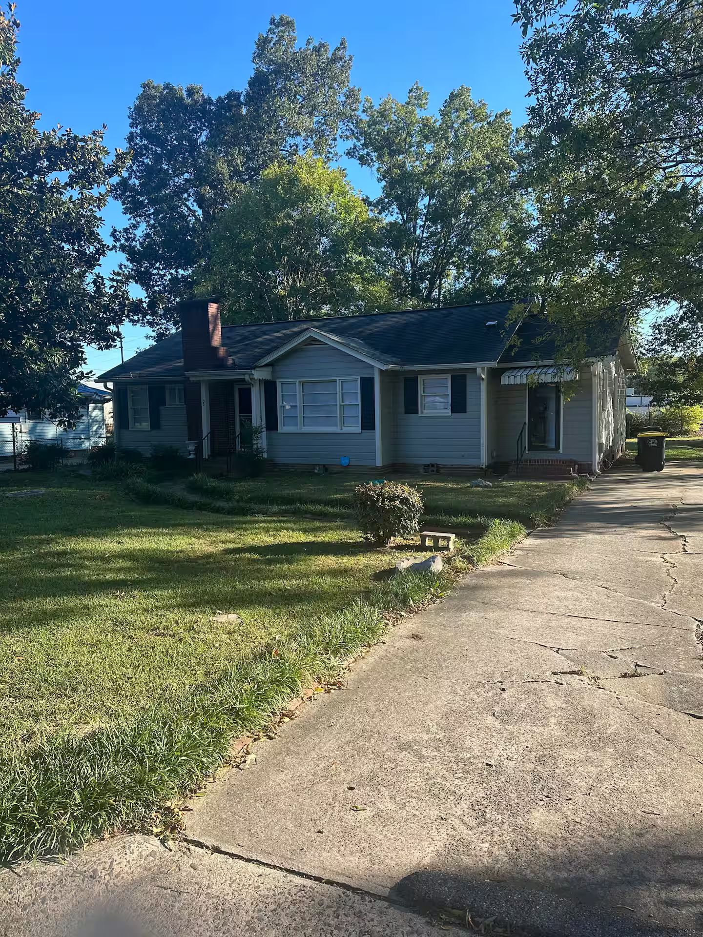 A single-story house with a front porch, a small front yard, and a driveway leading to the front door.