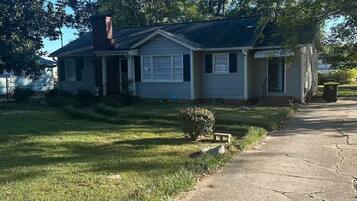 A single-story house with a front porch, a small front yard, and a driveway leading to the front door.