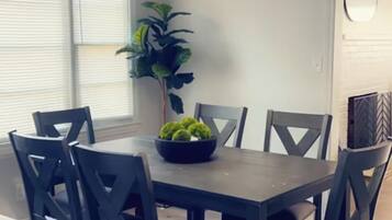 A dining area with a table and chairs, a hanging light fixture, and a potted plant.