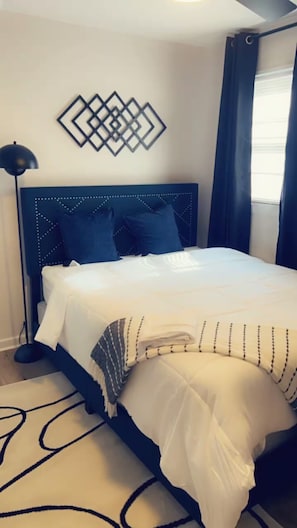 A neatly made bed with a headboard, a bedside lamp, and a geometric wall decoration. - Heloise Haven (Rome)