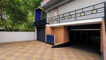 A building with a flat roof, a gated entrance, and a paved courtyard.