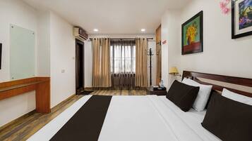 A hotel room with a bed, bedside table, lamp, and a painting on the wall.