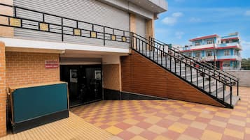 A building with a staircase leading to a second floor, a brick wall, and a tiled entrance area.