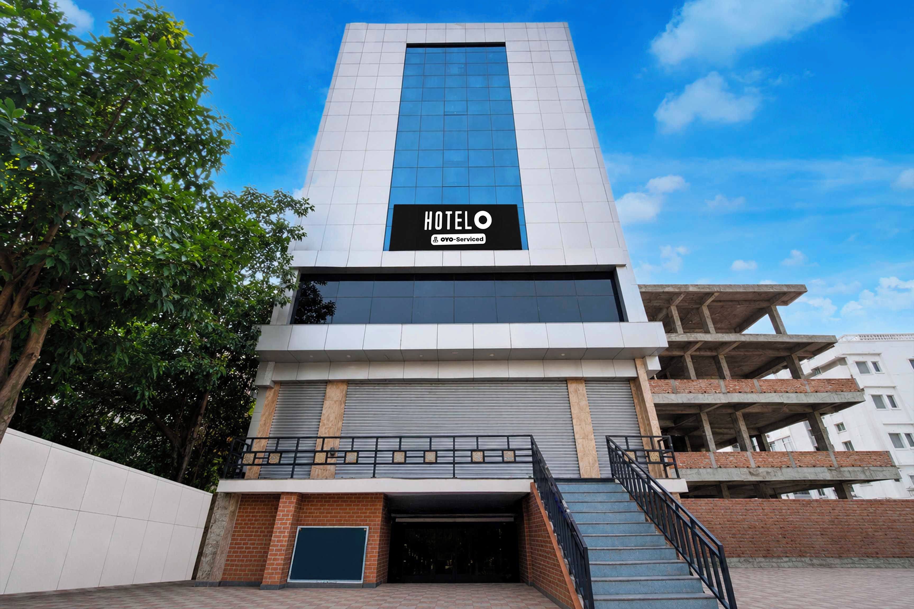 A modern hotel with a prominent glass facade, a visible entrance, and a staircase leading to the entrance.